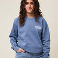 Front view of woman wearing a light blue crewneck sweatshirt with a small white Everytown for Gun Safety logo printed on left chest.