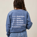 Back view of woman wearing a light blue crewneck sweatshirt with large white print that reads: Every American. Every Voter. Every Student. Every Survivor. Every Community. Everytown.