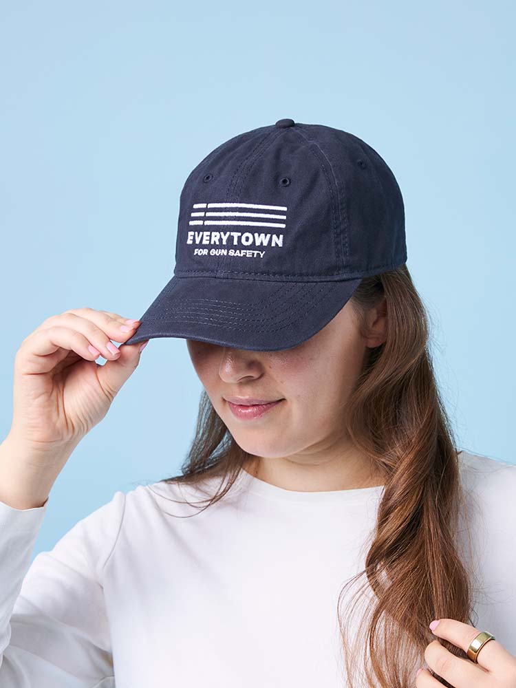 Person wearing a navy blue ballcap with a white Everytown for Gun Safety logo embroidered on the front.