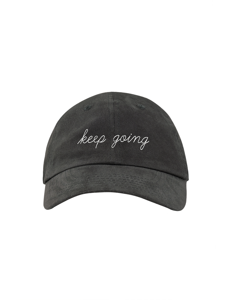 Front view of a gray ballcap with white embroidery that reads KEEP GOING in script font.