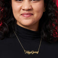 Woman wearing a gold name plate style necklace with the phrase Keep Going in script font.