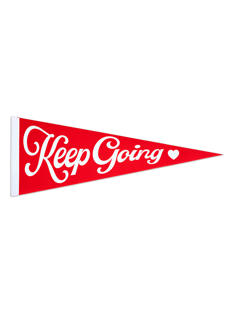 Red felt pennant with white cursive text  that reads Keep Going with a white heart to the right of the text