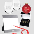 Set of 2 etched wine glasses with Moms Demand Action logo, silver 5x7 inch picture frame with white Moms Demand Action logo, red, sparkly round ornament with white text that reads One Tough Mother in script font with a white heart around it, a gold nameplate-style necklace that reads Keep Going in script font, and red shoelaces with white text that read Keep Going.