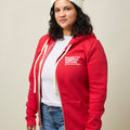 Front view of woman wearing a red zip-up hooded sweatshirt with two front pockets and a small white Moms Demand Action logo printed on left chest.
