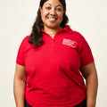 Woman wearing a red polo short sleeve shirt with a white embroidered Moms Demand Action logo on left chest.
