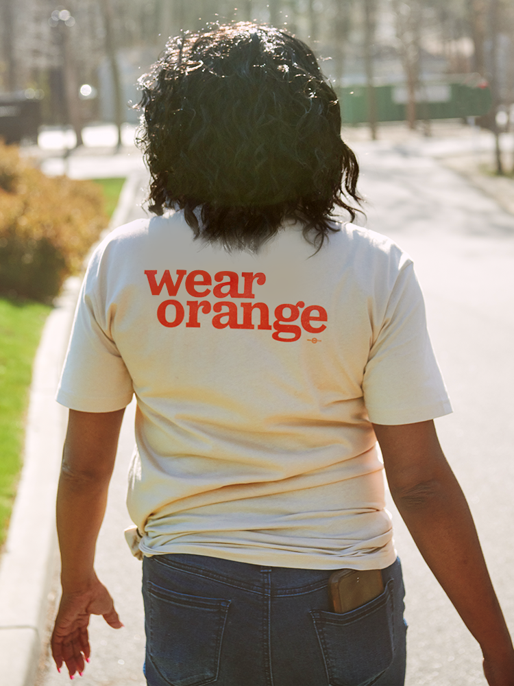 Back of cream colored short sleeve t-shirt that reads wear orange in bright orange, bold, lowercase letters