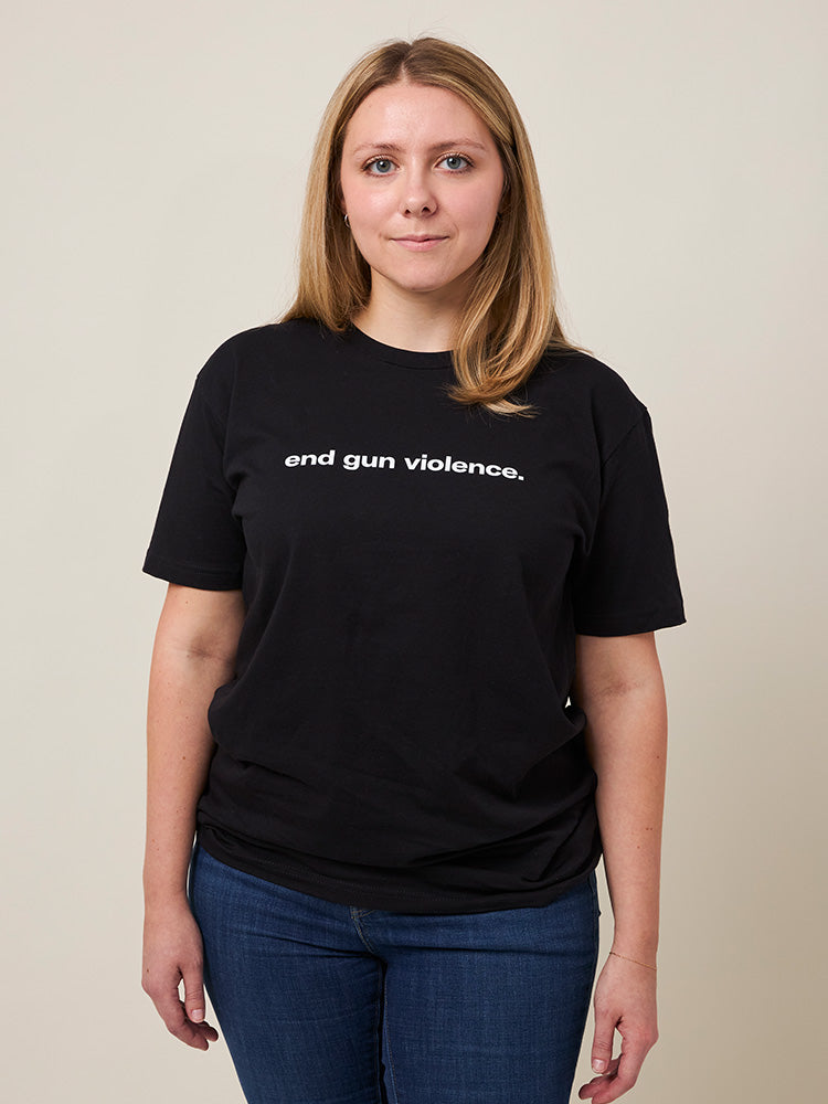 Front view of woman wearing a black unisex short sleeve t-shirt that reads end gun violence. in lowercase bold, white print.
