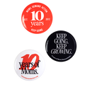 Image of three buttons. A red button with white text reads "Moms Demand Action 10 Years, EST 2012, Keep Going." A black button with white text reads "Keep Going. Keep Growing." in all caps. Small text along the bottom reads "10 years of Moms Demand Action." A white button with red and black text reads "10 years of Moms. momsdemandaction.org"